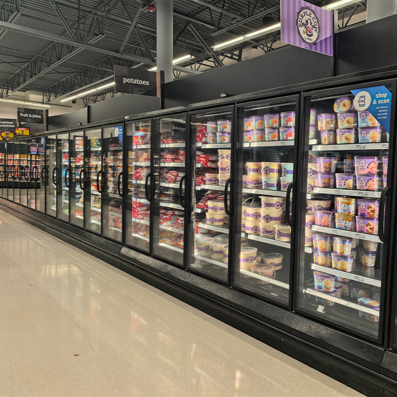 Glass-door vertical freezer display cases showing ice cream and frozen food in a retail aisle