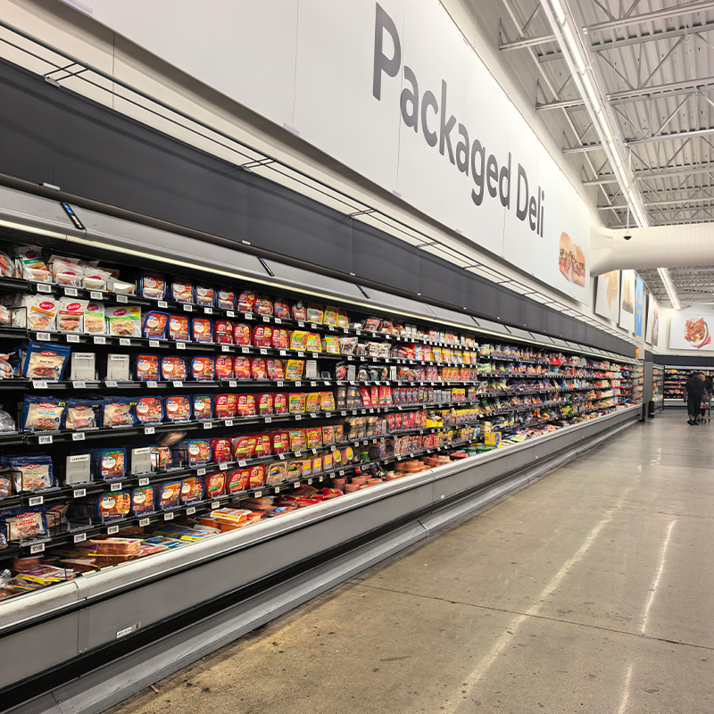Open multideck refrigerated display cases with packaged chilled food in a retail aisle