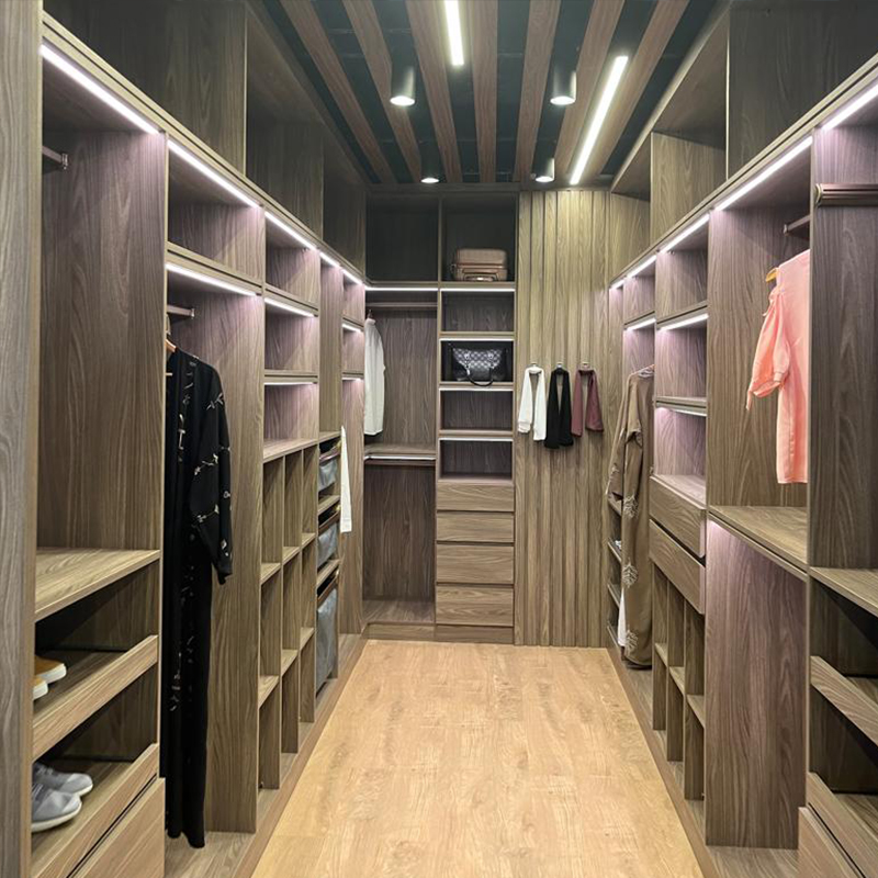Walk-in wardrobe with illuminated wooden shelving and clothing compartments