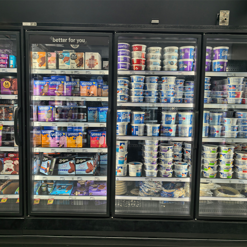 Front view of illuminated glass-door freezer cases displaying ice cream and frozen products