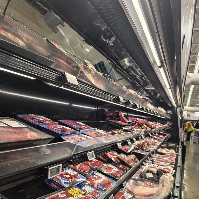 Under-shelf lighting above packaged meat in an open refrigerated display case