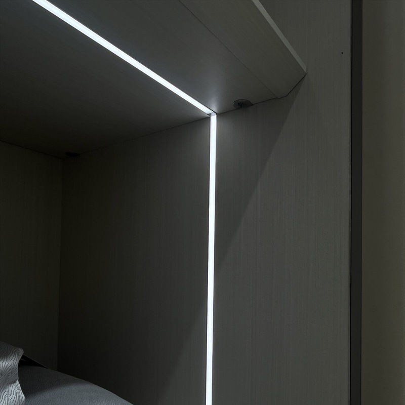 Close view of a lit horizontal shelf edge beside a vertical light line in wooden display furniture