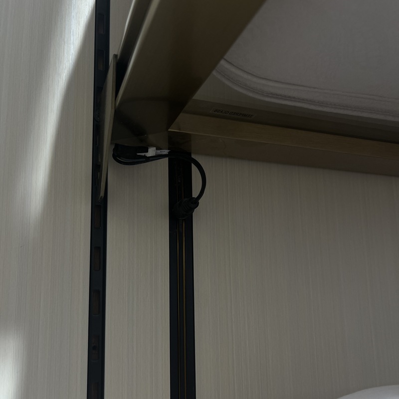 Cable lead and connector visible near the side of a wooden display shelf